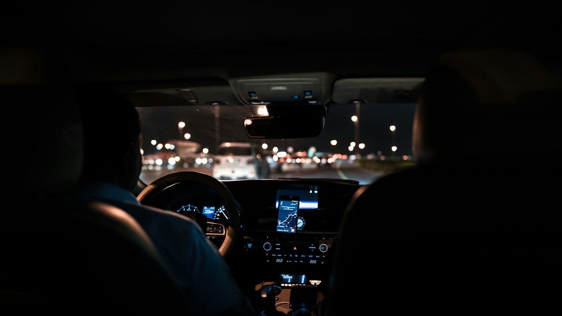 A driver at the wheel at night, seen from the back seat